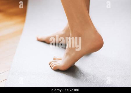 Eine Seitenansicht aus der Nähe von einer nicht erkennbaren Frau, die barfuß auf einem warmen, beheizten Holzboden stand Stockfoto