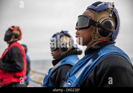 OSTSEE (Okt 24, 2022) Retail Services Specialist 2. Klasse Jakerion Brown, rechts, wartet darauf, Unterlegkeile und Ketten von einem MH-60R Seahawk-Hubschrauber zu entfernen, der am Hubschrauber Maritime Strike Squadron (HSM) 79 auf dem Flugdeck des Arleigh Burke-Klasse-Lenkflugkörper-Zerstörers USS Roosevelt (DDG 80) befestigt ist, 24. Oktober 2022. Roosevelt befindet sich im geplanten Einsatzgebiet der US Naval Forces Europe, das von der Sechsten Flotte der USA eingesetzt wird, um die Interessen der USA, der Alliierten und der Partner zu verteidigen. Stockfoto