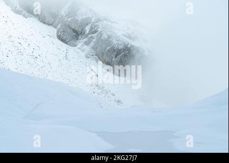 Nebeliger, schneebedeckter Berg und gefrorener See Stockfoto