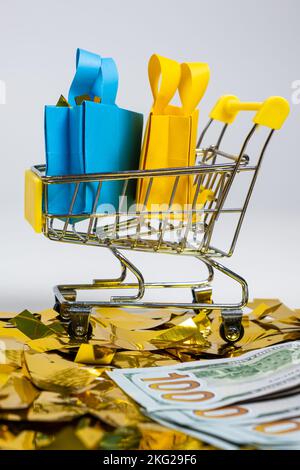Einkaufstaschen im Einkaufswagen und Geld auf Pailletten auf weißem Hintergrund. Das Konzept des Verkaufs. Stockfoto