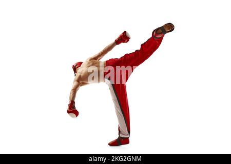 Junge professionelle Kickboxer trägt Helm und Boxhandschuhe in Bewegung isoliert auf weißem Hintergrund. Sport, Wettkampf, Energie, Kampfsport Stockfoto