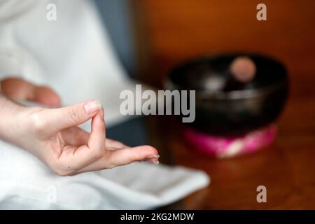 Tibetische Schale wird in der Klangtherapie, Meditation und Yoga verwendet. Buddhistische Frau, die eine Klangschale für die Klangetherapie in der Atmosphäre zur Heilung praktiziert, medi Stockfoto