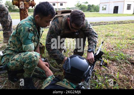 US Marine Corps Staff Sgt. Shane McDaniel, Zentrum, eine Aufklärungsmarine der Streitkräfte mit dem Kommandoelement der Marine Expeditionary Unit 11., I Marine Expeditionary Force, unterstützt Soldaten der Royal Brunei Land Force (RBLF) mit 2. Bataillons, RBLF in einer Sanierungsmaßnahme eines L7A2-Mehrzweck-Maschinengewehrs während einer praktischen Anwendung städtischer Operationen während der Zusammenarbeit über die Bereitschaftlichkeit und Ausbildung (CARAT) Brunei 2022 im FIBUA Village, Brunei, 25. Oktober 2022. CARAT Brunei 2022 hebt das 28.-jährige Jubiläum VON CARAT unter Verbündeten und Partnern hervor, um ein langfristiges Engagement für die CARAT-GRUPPE zu demonstrieren Stockfoto