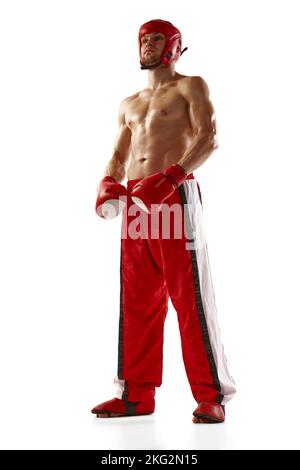 Kräftiger und muskulös getrackter Kickboxer in roter Sportkleidung und Boxhandschuhe auf weißem Hintergrund. Gemischte Kampfkünste, Sport, Sieg, Sieg und Stockfoto