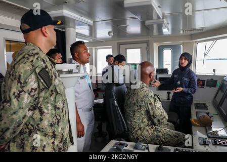 221025-N-FO714-1171 MUARA, Brunei (Okt 25, 2022) Royal Brunei Navy LT. j.g. Hayat Nabilah, amtierender Navigationsoffizier des Offshore-Patrouillenschiffs KDB Daruttaqwa (DTQ 09) der Darussalam-Klasse, führt Kapitän Walter Mainor, Kommandant der Task Force 71 und Cmdr, durch das Pilothaus des Schiffes. Clayton Beas, Kommandant des Litoral Combat Ship USS Charleston (LCS 18) während der Cooperation afloat Readiness and Training (CARAT) Brunei, Oktober 25. CARAT Brunei 2022 hebt das 28.-jährige Bestehen von CARAT unter Alliierten und Partnern hervor, um ein langfristiges Engagement für Stärke zu demonstrieren Stockfoto