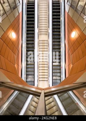 Weitwinkelansicht von oben nach unten. Symmetrische Balance. Lange Rolltreppen im U-Bahnhof Singapur. SMRT. Stockfoto