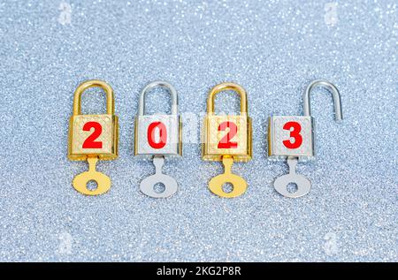 Eröffnung im neuen Jahr 2023: Reihe mit vier glänzenden Vorhängeschlössern mit isolierten Generalschlüsseln auf glänzendem Hintergrund. Stockfoto