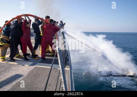 221026-N-EH998-1096 GOLF VON ADEN (OKT. 26, 2022) Seeleute an Bord des Lenkrakenzerstörers USS Nitze (DDG 94) arbeiten daran, ein Feuer an Bord eines zivilen Motorbootes im Golf von Aden zu löschen, Oktober 26. Nitze wird im Einsatzgebiet der US-Flotte für 5. eingesetzt, um die Sicherheit und Stabilität der Seefahrt im Nahen Osten zu gewährleisten. Stockfoto