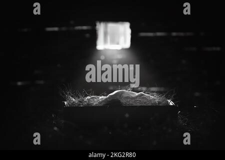 Helles Licht aus dem Fenster beleuchtet das Jesuskind in der Krippe, Weihnachten und Weihnachten im Hintergrund, um die Geburt Jesu Christi zu feiern Stockfoto