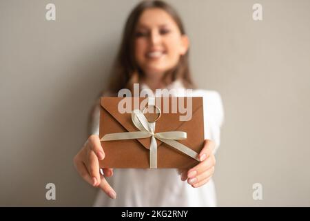 Einladungskarte oder Geschenkgutschein in weiblichen Händen. Konzentrieren Sie sich auf Hände, unscharf Gesichts in Hintergrund Nahaufnahme. Stockfoto