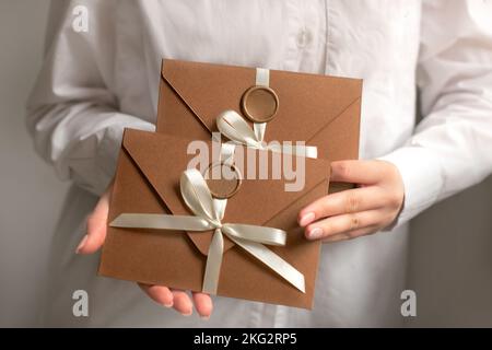 Handgefertigte Briefumschläge aus Bronze speichern die Datumskarten in Frauenhand. Der Geschenkgutschein ist das beste Geschenk Stockfoto