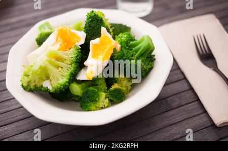 Gesunde Ernährung. Gedämpfte Brokkoli-Blütenstände mit gekochtem Ei in einer Schüssel Stockfoto