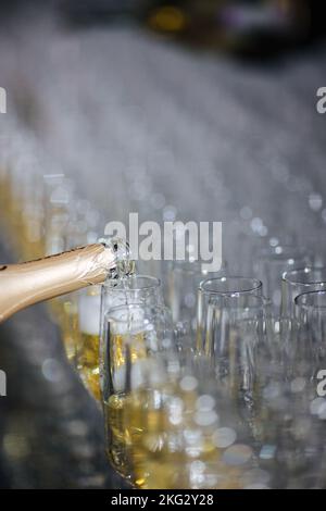 Champagner, der Gläser aus einer Flasche eingießt. Spritzer und Tropfen. Konzept für den Urlaub. Stockfoto