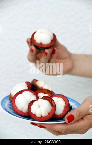 Mangostan-Frucht auf einem Teller gespalten. Tropische Frucht mit süßem saftigen weißen Segme. Vietnam. Stockfoto