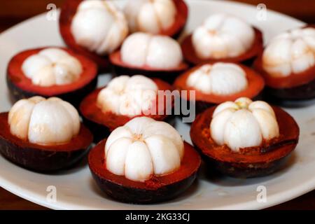 Mangostan-Frucht auf einem Teller gespalten. Tropische Frucht mit süßem saftigen weißen Segme. Vietnam. Stockfoto