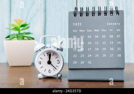 Januar 2023 Monatlicher Tischkalender für 2023 Jahr mit Wecker auf blauem Holzhintergrund. Stockfoto