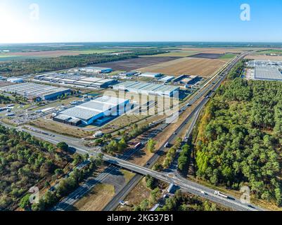 Panoramaaufnahme des weiten Bereichs des Lagerhauses, umgeben von üppigem Grün in der Nähe einer bebauten Brücke und Autobahn Stockfoto