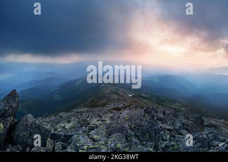 Dunkle Berglandschaft mit dramatischem Himmel vor dem Sturm und Felsen im Vordergrund Stockfoto