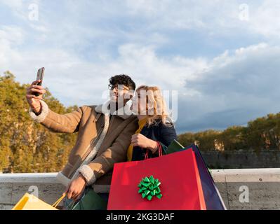 Multirassisches Paar, das nach dem Einkaufen ein sehr glückliches Selfie macht Stockfoto