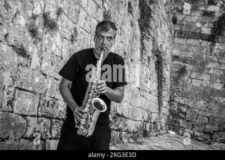 Ein Musiker spielt Posaune vor einer Steinmauer auf Kreta Griechenland Stockfoto