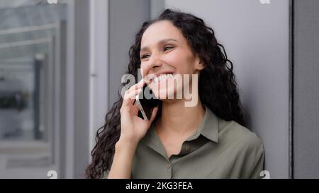 Fröhlich lachend glücklich unbeschwert Frau in der Stadt im Freien Anruf annehmen Gespräch per Smartphone chatten mit Freunden Freund 30s Stockfoto