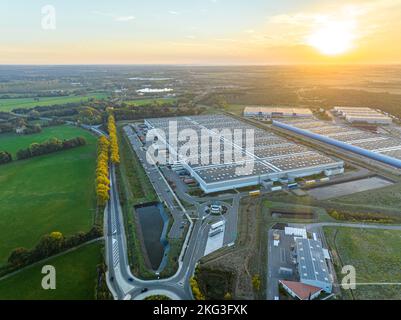 Drohnenaufnahme großer Lagerhausgrundstücke mit üppigem Grün und geparkten Fahrzeugen im Val d'Oise, Frankreich Stockfoto