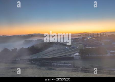 Die Rennbahn Goodwood im Morgengrauen mit einem sanften Nebel, der über die Rennbahn in der Nähe von Chichester, West Sussex, im South Downs National Park strömt. Stockfoto