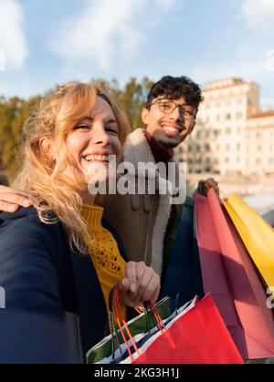 Glückliche Freunde, die ein Selfie in der Stadt machen und Einkaufstüten in der Hand halten Stockfoto