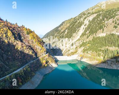 Drohnenaufnahme des Gittaz-Sees mit Dammwänden, umgeben von üppigen Bergen, ein französisches Wunder der Wasserkraft Stockfoto