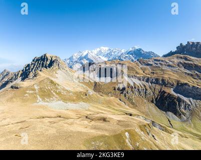 Panoramablick aus der Vogelperspektive auf trockene Graslandhügel im Sommer mit schneebedeckten französischen alpen Stockfoto