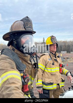 Ein Feuerwehrmann, der der Feuerwehr Duluth zugewiesen wurde, reagiert mit Unterstützung eines Ausbilders auf einen Strukturbrand während einer Live-Brandentwicklung im Emergency Response Training Center des Lake Superior College, Duluth, Minnesota, am 27. Oktober 2022. Die Feuerwehr 148., die Feuerwehr Duluth und die höhere Feuerwehr haben gemeinsam einen zweiwöchigen, praktischen Abschlusskurs veranstaltet, der den neuen Feuerwehrleuten helfen soll, in ihrer neuen Karriere erfolgreich zu sein und Trainingspläne für die Feuerwehr in der Region zu standardisieren. (Foto der Air National Guard von Audra Flanagan) Stockfoto