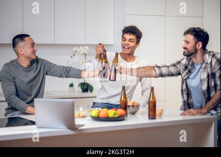Männer, die in der Küche ein alkoholisches Getränk trinken Stockfoto