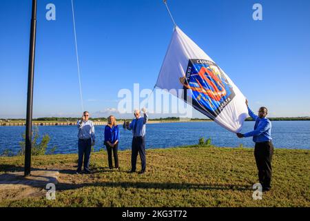 SpaceX Crew-5 Flaggenanhebung. Die Mitarbeiter des NASA Commercial Crew Program (CCP), Tyrell Hawkins (rechts) und Henry May (zweiter von rechts), heben am 3. Oktober 2022 die Crew-5-Flagge nahe der Countdown-Uhr auf der Pressestelle im Kennedy Space Center der NASA in Florida an. Neben May ist seine Frau und links der CCP-Manager Steve Stich. Die NASA-Mission SpaceX Crew-5 wird die NASA-Astronauten Josh Cassada und Nicole Aunapu Mann, den Roskosmos-Kosmonauten Anna Kikina und JAXA (Japan Aerospace Exploration Agency) zur Internationalen Raumstation für eine Wissenschaftsexpedition im Rahmen der KPCh der Agentur bringen. SpaceX’s Stockfoto