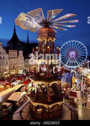 21. November 2022, Mecklenburg-Vorpommern, Rostock: Nach der Eröffnung des Weihnachtsmarktes sind die Besucher auf dem Neuen Markt vor der Marienkirche unterwegs, eine große Weihnachtspyramide überragt alles. Der Rostocker Weihnachtsmarkt mit seiner 3,2 Kilometer langen Promenade, 16 Karussells und 50 geschmückten Kaufmannsständen ist bis zum 22. Dezember 2022 geöffnet. Foto: Bernd Wüstneck/dpa Stockfoto