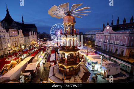 21. November 2022, Mecklenburg-Vorpommern, Rostock: Nach der Eröffnung des Weihnachtsmarktes sind die Besucher auf dem Neuen Markt vor der Marienkirche unterwegs, eine große Weihnachtspyramide überragt alles. Der Rostocker Weihnachtsmarkt mit seiner 3,2 Kilometer langen Promenade, 16 Karussells und 50 geschmückten Kaufmannsständen ist bis zum 22. Dezember 2022 geöffnet. Foto: Bernd Wüstneck/dpa Stockfoto