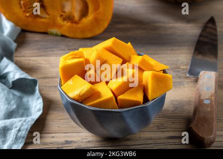 Schüssel mit frisch geschnittenem Kürbis auf einem hölzernen Küchentisch Stockfoto