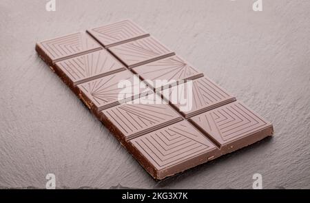 Ein Stück bittere dunkle Schokolade auf einem Schieferstein, Makro. Stockfoto