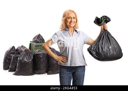 Lächelnde reife Frau wirft einen Plastikmüllbeutel isoliert auf weißem Hintergrund Stockfoto