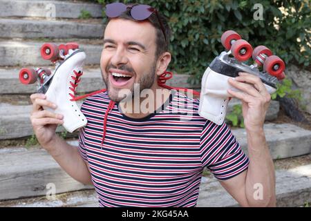 Mann mit 1980er-Look, der Rollschuhe hält Stockfoto