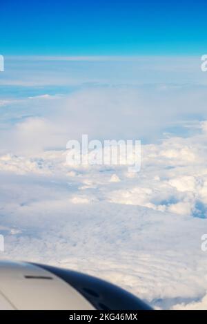 Blick von der Boeing 737 MAX 8 auf White Air Clouds und Clear Blue Sky. Weiß-graues Motorgehäuse mit Leitschaufeln im Rahmen. Stockfoto