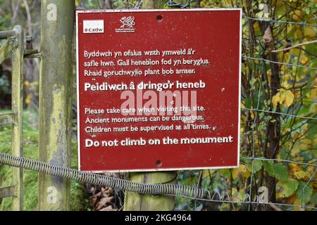 Rotes Schild mit öffentlichen Informationen aus Gusseisen (steigen Sie nicht auf das Denkmal) am Eingang zum St. CyBi's Brunnen, Llyn Peninsular, North Wales Stockfoto