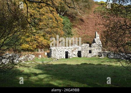 St. Cybis Brunnenpfleger/Hüter Cottage, (Llyn Peninsular North Wales) Brunnenkammer und Ruinen der kleinen abgelösten Latrinengebäude im Herbst Stockfoto