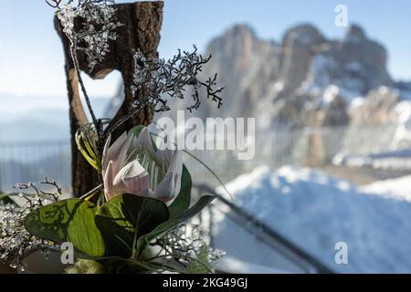 Eine Komposition aus Holz mit Herz und künstlicher Blume steht vor dem Hintergrund einer Bergkette Stockfoto