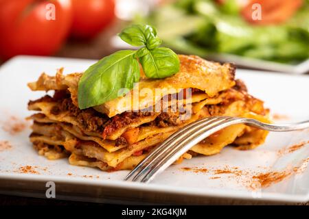 Lasagne auf einem Teller mit Salat auf Holz Stockfoto
