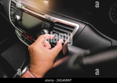 Der Fahrer passt die Windrichtung der Fahrzeugluftklappe im Fahrzeug an. Stockfoto