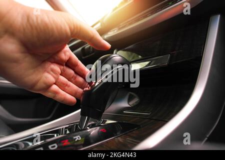Die Fahrerhand setzt den Schalthebel, um die automatische Gangposition im Fahrzeug zu ändern. Stockfoto