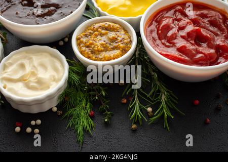 Verschiedene Saucen in Schalen mit Gewürzen, Rosmarin und Dill, Thymian und Pfefferkörner Stockfoto