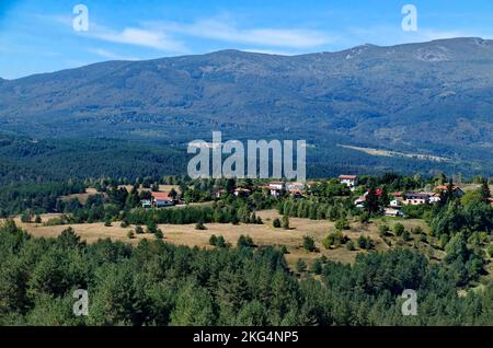 Szene mit Herbstwiese, Wald und Wohnviertel des bulgarischen Dorfes Plana im Berg Plana, Bulgarien Stockfoto