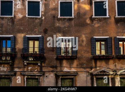 Das Bild von Venedig italien zeigt die typische venezianische Szene eines alten Gebäudes mit Fensterläden und Reflexionen. Das Sonnenlicht fällt auf das Gebäude Stockfoto