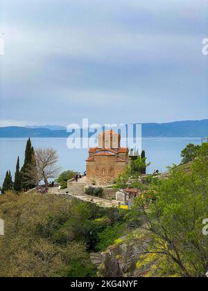 Eine vertikale Aufnahme der Kirche des heiligen Johannes des Theologen auf der Klippe mit dem Ohridsee im Hintergrund Stockfoto